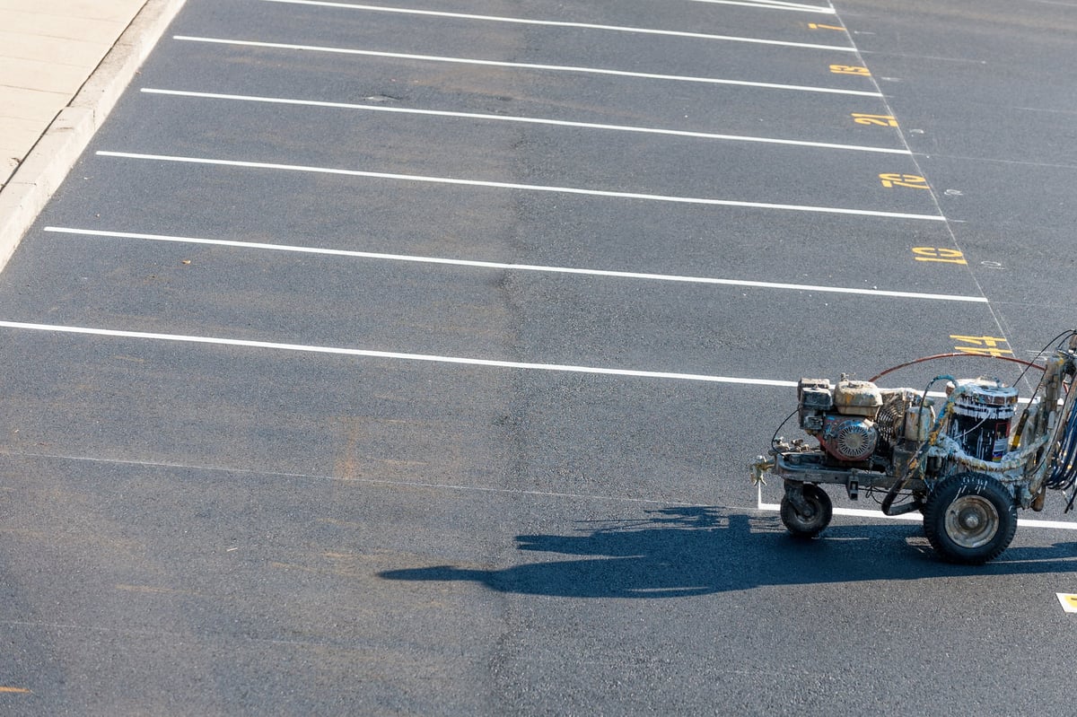 Worker striping commercial parking lot